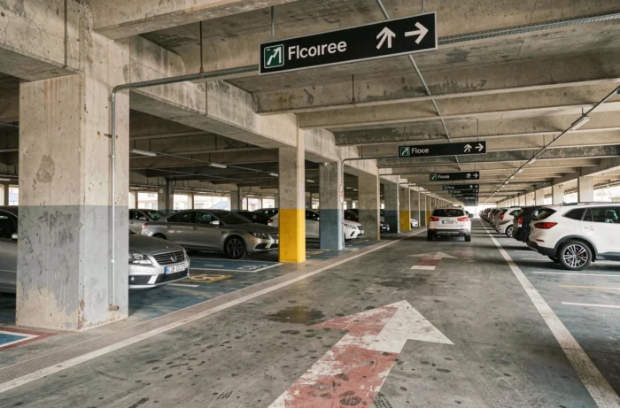 Intérieur d'un parking couvert à étages près de la gare de Valence TGV avec signalisation et voitures garées
